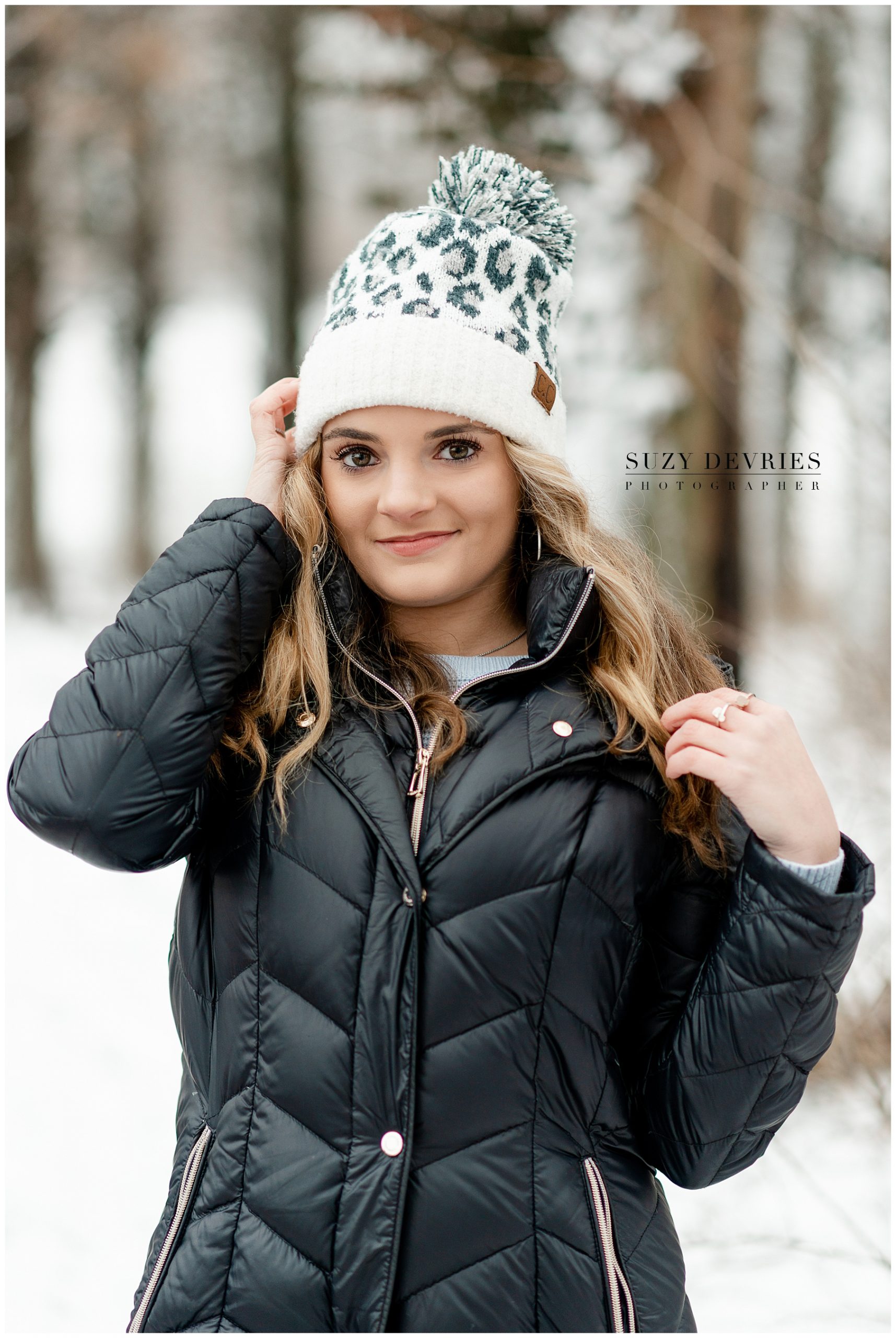 Edwardsville High School Senior girl in the snow wearing a black coat and leopard hat.